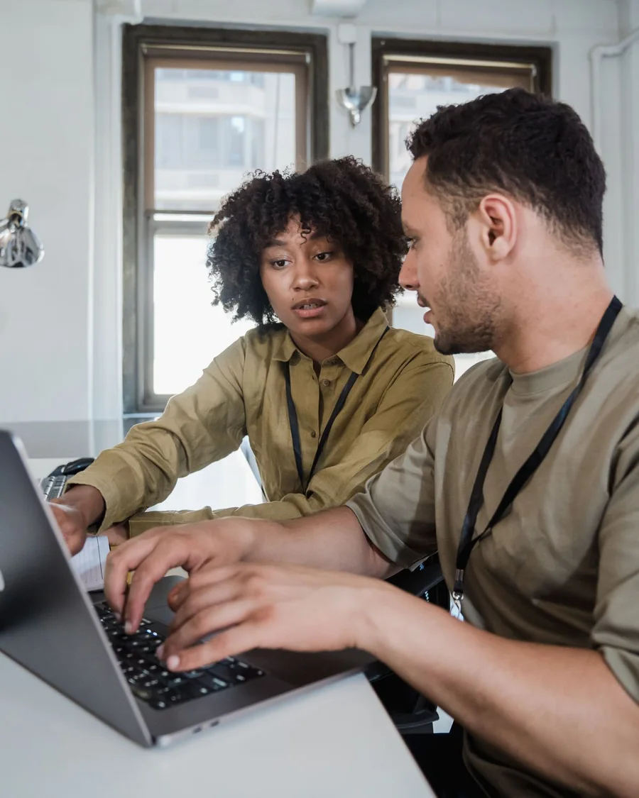 A woman and a man working together on a laptop in an office.